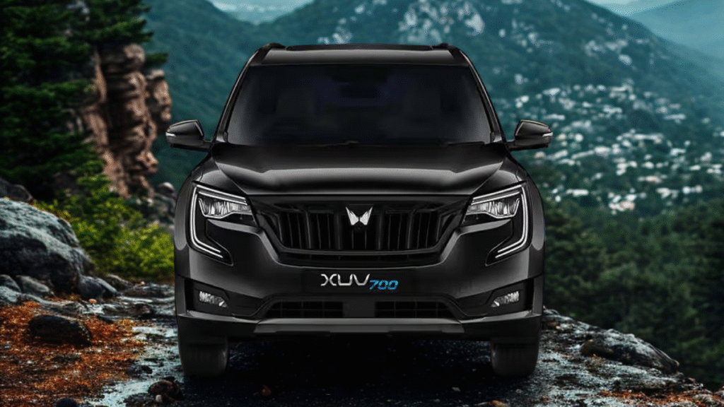 Mahindra XUV700 driving through desert dunes with sand trail and sunset sky