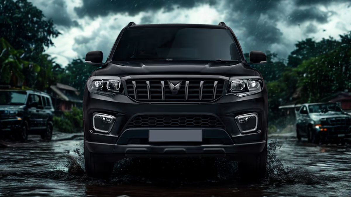 Mahindra Scorpio N splashing through muddy monsoon roads in a green village setting, captured mid-action under stormy clouds to depict strength in extreme weather.